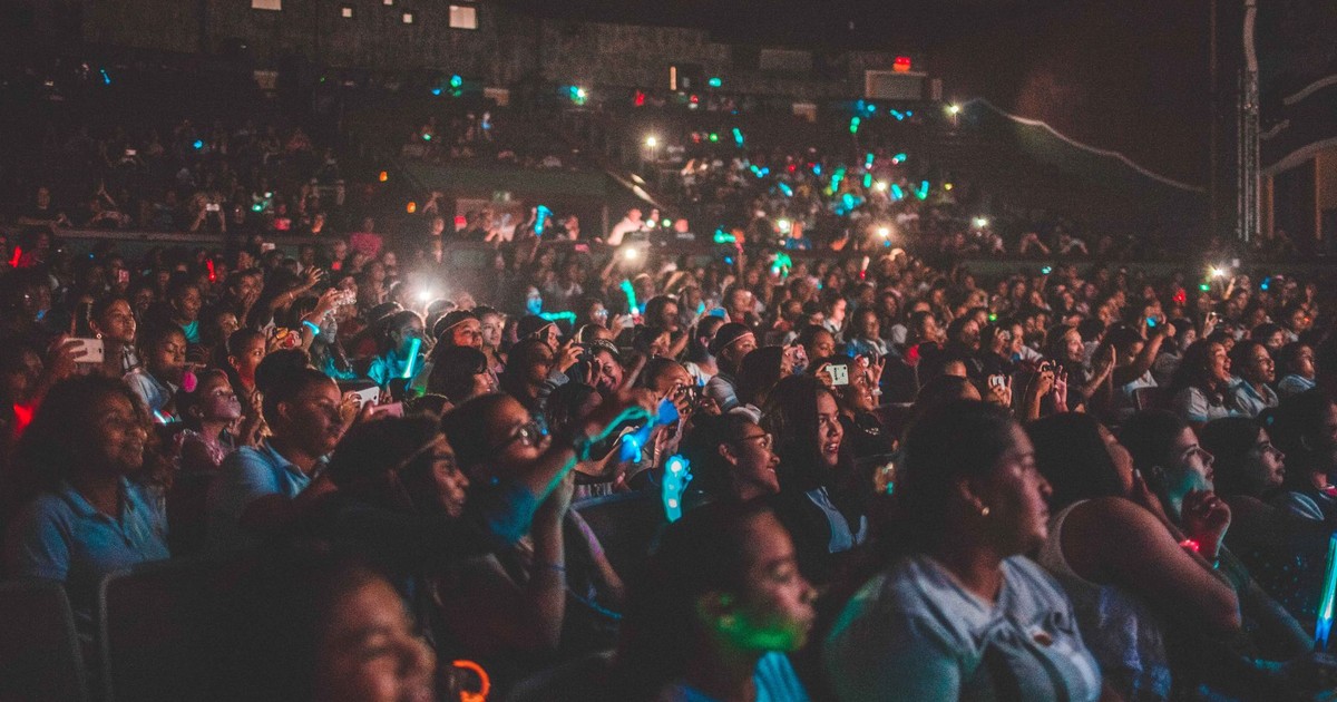 A vibrant audience enjoying a live music concert with colorful lights in a large venue.