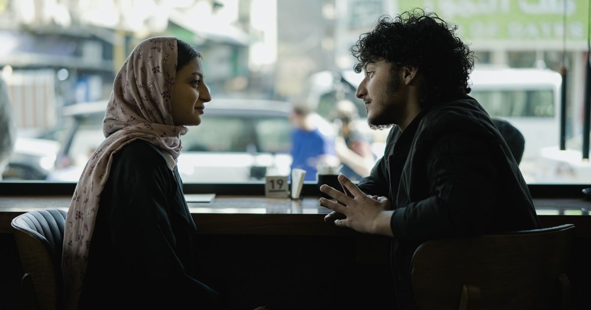 Two adults engage in a deep conversation over coffee in a cozy cafe setting.