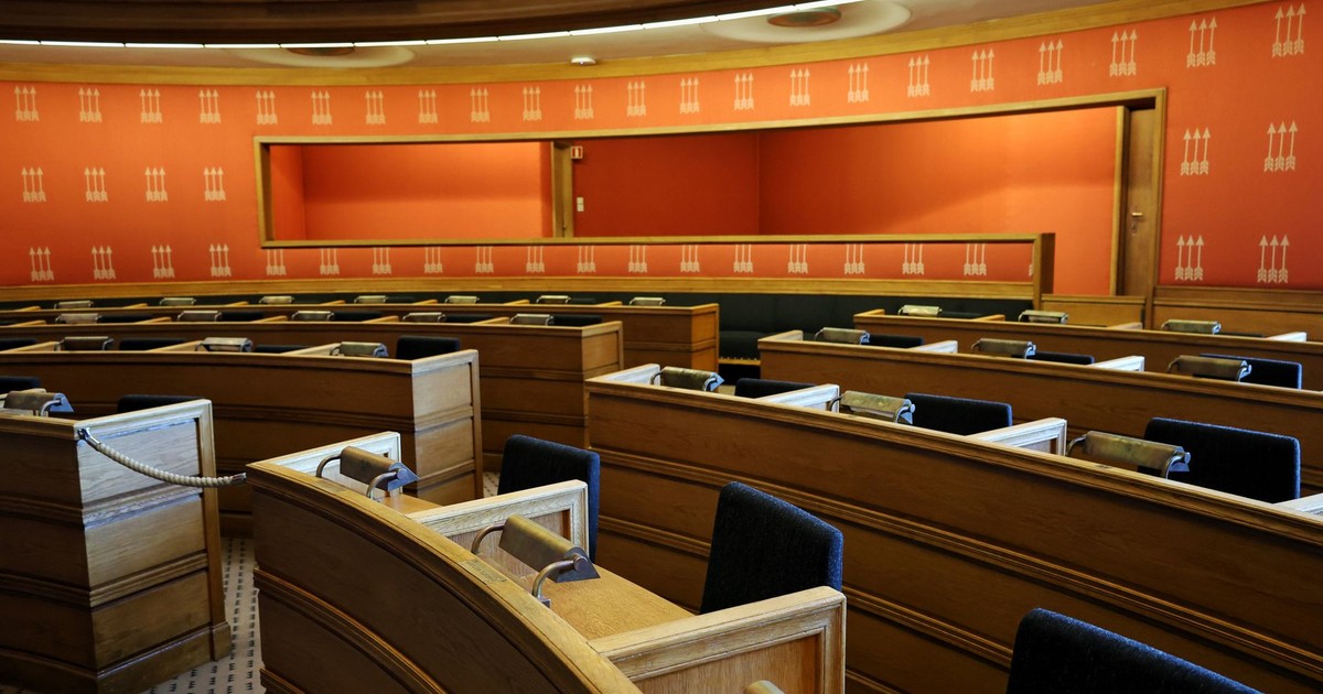 An empty parliamentary meeting room with wooden seating and vibrant orange walls in Oslo, Norway.