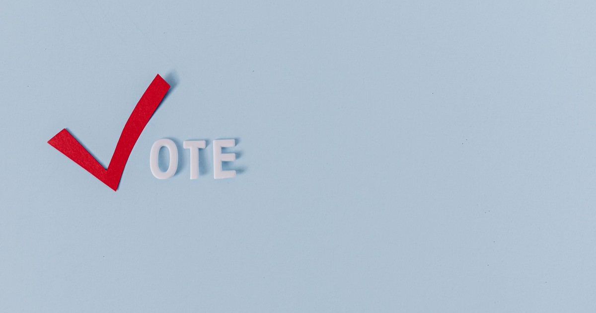 Red checkmark and 'vote' text on light blue background, symbolizing election and political choice.