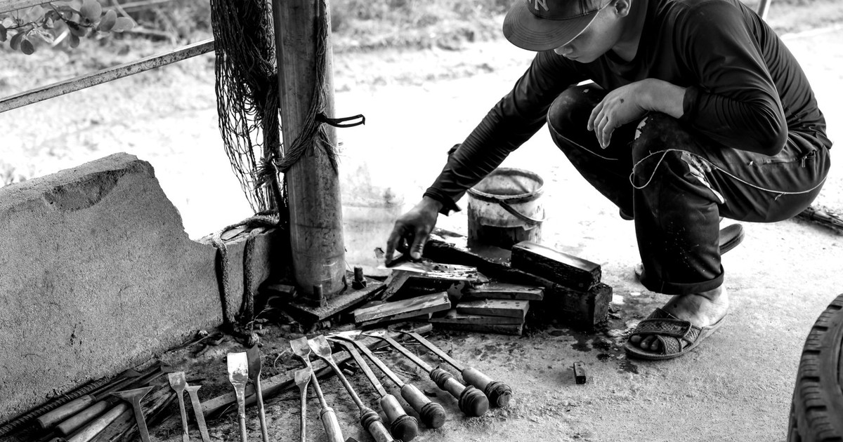 A craftsman working with chisels and tools outside on a sunny day.