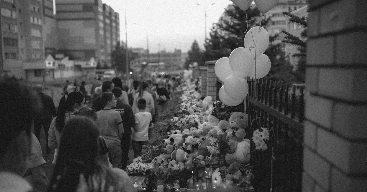 Memorial gathering in Kazan, Russia with flowers, balloons, and people in mourning.
