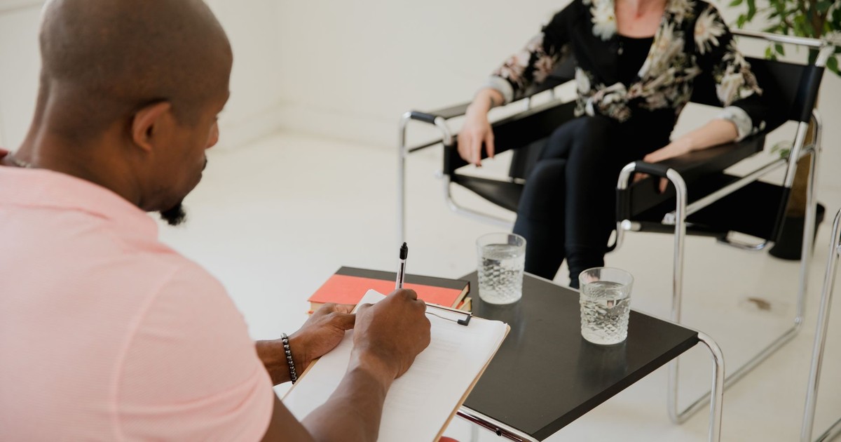 A therapist taking notes during a session, providing mental health support indoors.