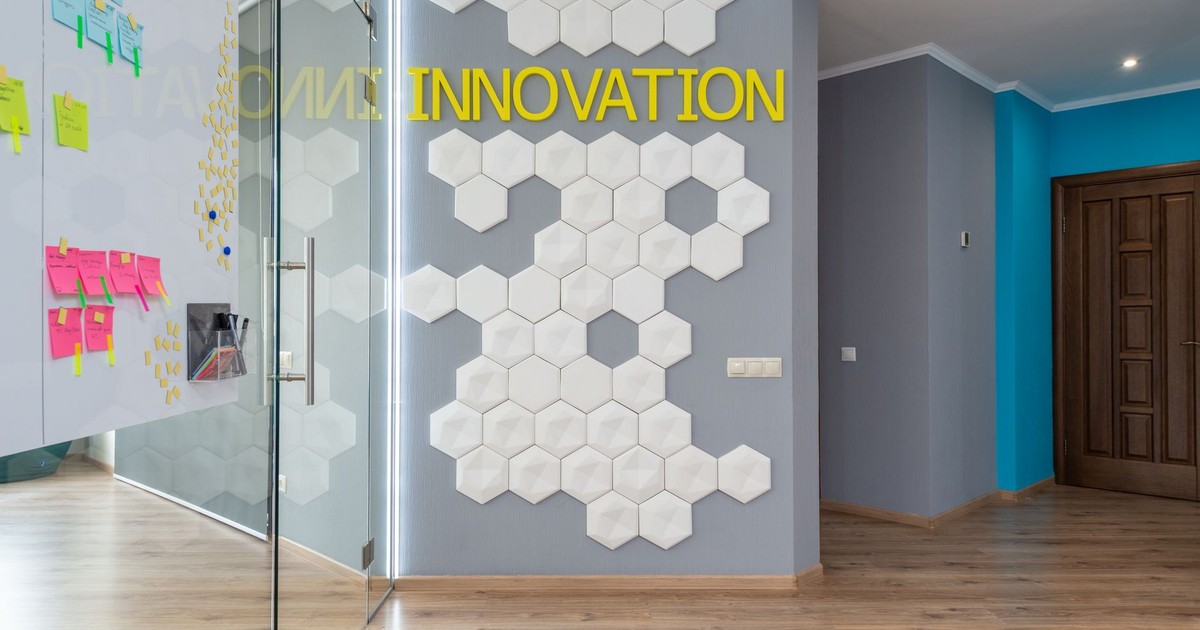 Geometric decoration on wall with Innovation inscription near glass door of conference room with colorful stickers in hallway of office building