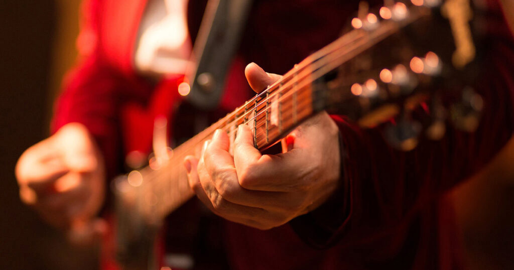 Guitar player fingers on guitar, available light, high iso shot, shallow depth of field