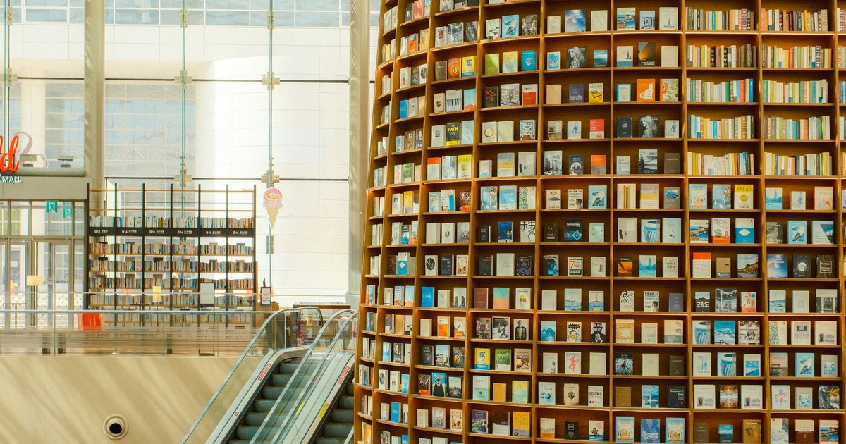 A stunning interior of a modern library featuring towering bookshelves and an escalator.