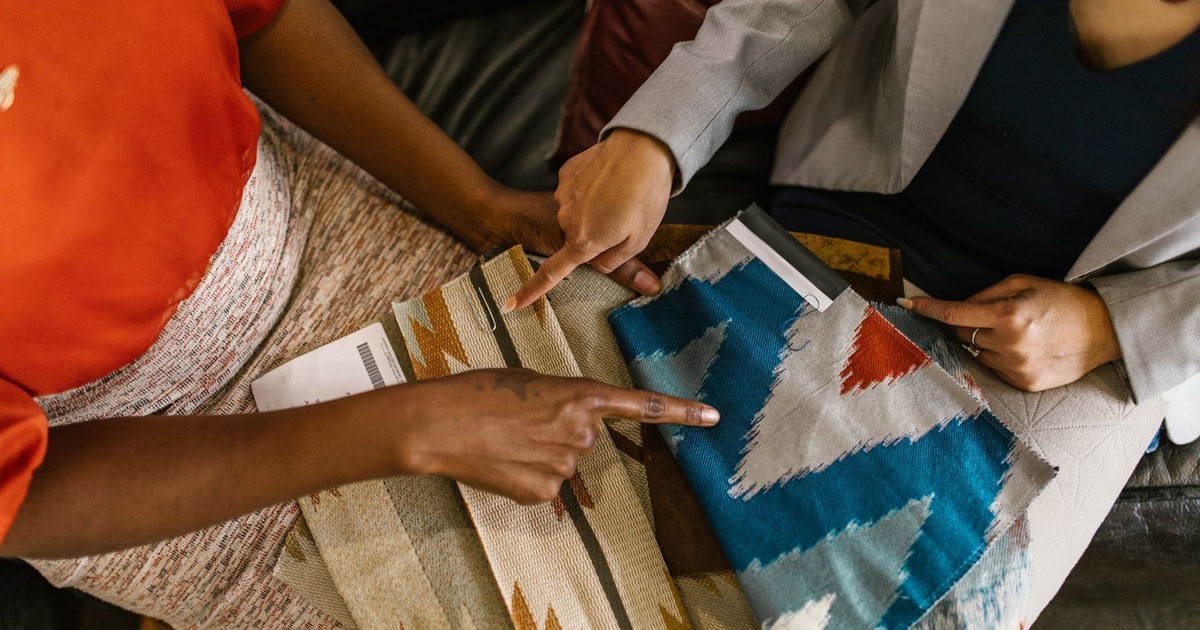 Two professionals assessing colorful fabric swatches for interior design project.