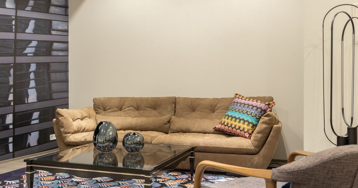 Interior of modern living room with comfortable sofa with colorful cushion and table on carpet near armchair
