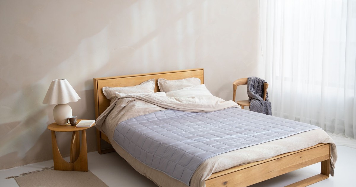 Bright minimalist bedroom featuring a wooden bed and cozy bedding.