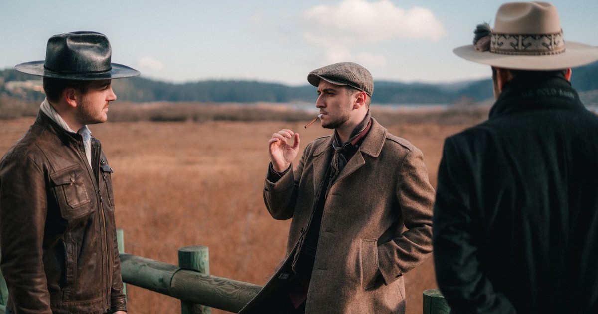 Three men in vintage attire engage in conversation in a scenic outdoor setting in Bolu, Turkey.