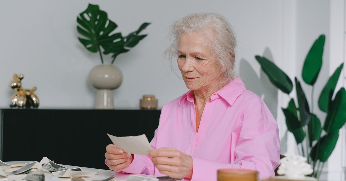 Elderly woman enjoying memories through old photographs, indoors setting.