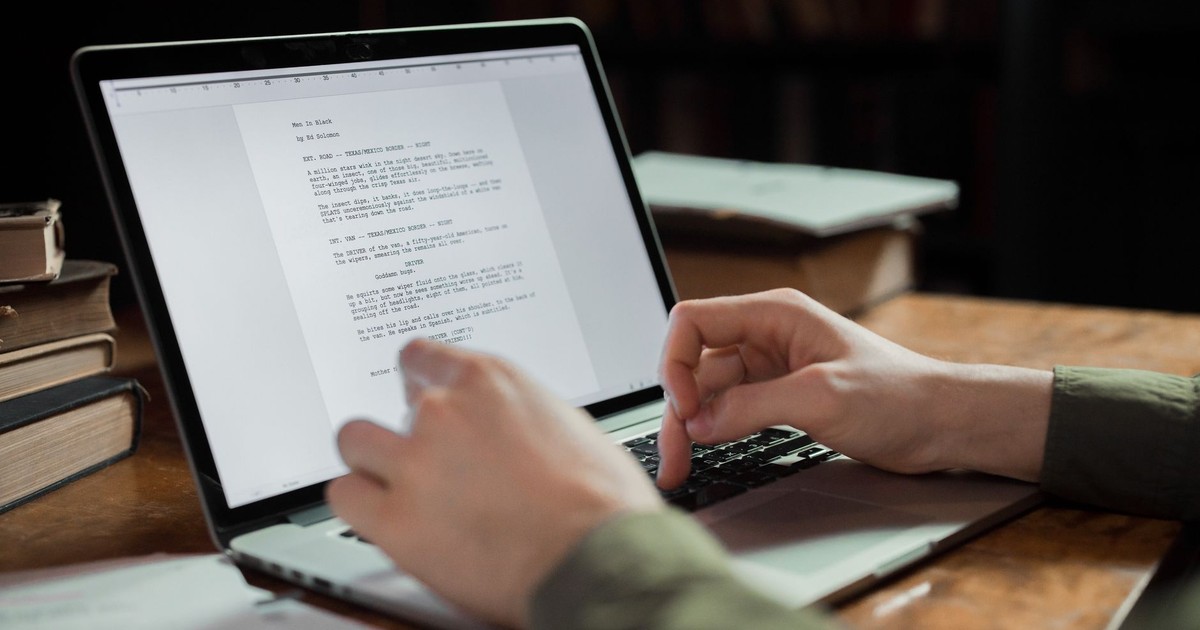 A person typing on a laptop in a cozy workspace with books around. Perfect for writing and technology themes.