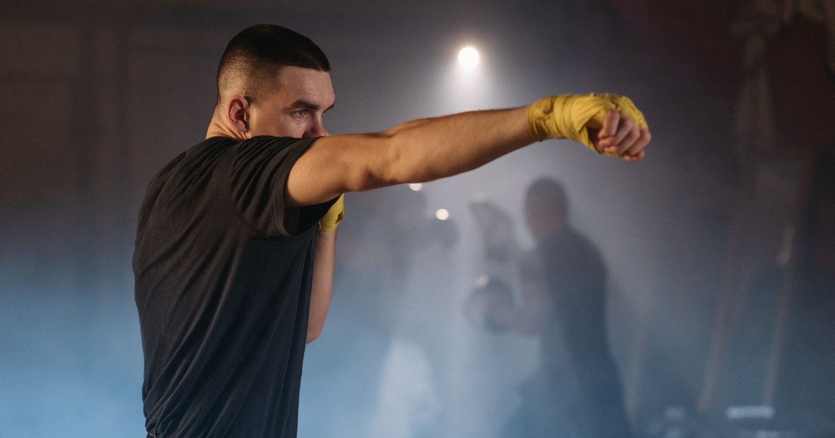 Focused boxer throwing a punch during intense training in a smoky gym.