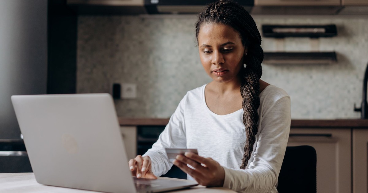 African American woman using laptop and credit card for online shopping at home.