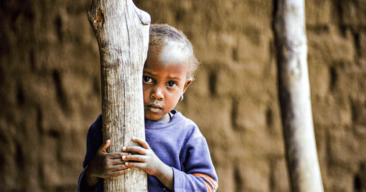 Portrait of a shy child peering behind a tree in Dodoma, Tanzania.