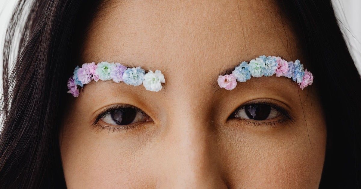 A close-up portrait of a woman with floral eyebrows, showcasing creative makeup art.