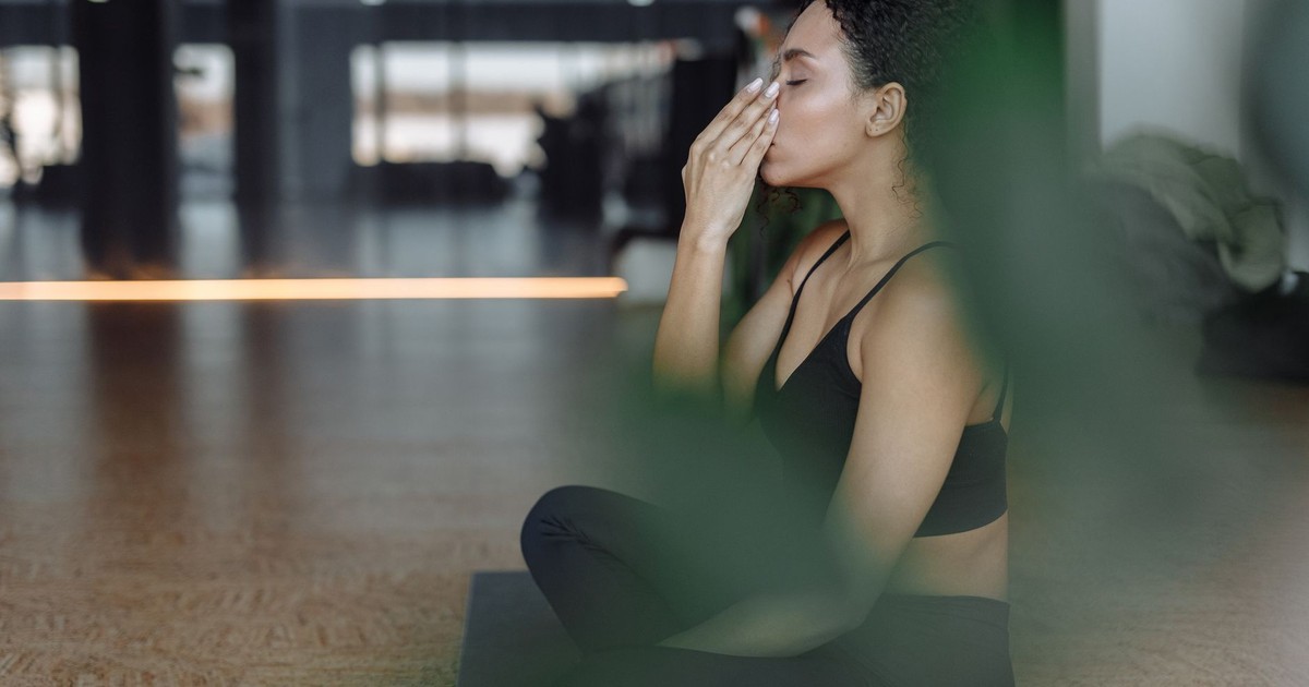 Peaceful woman practicing yoga indoors with eyes closed, focusing on breathing and relaxation.
