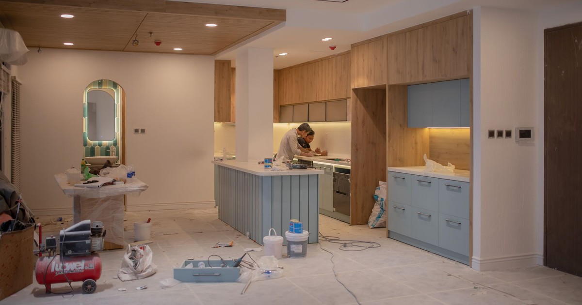 A modern kitchen undergoing renovation, featuring a worker, tools, and materials.