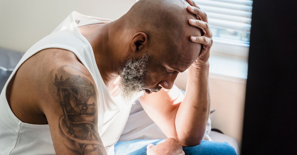 A senior man sits thoughtfully at home, conveying emotions of contemplation and stress.