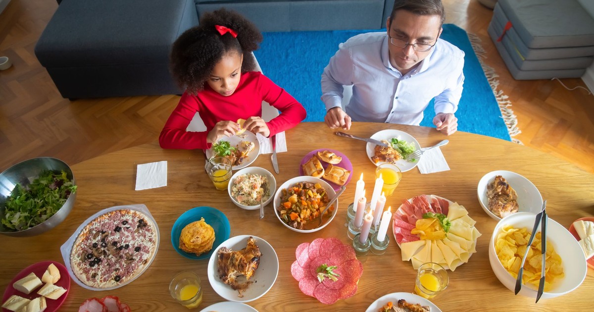 Father and daughter enjoying a diverse meal at home in Portugal.