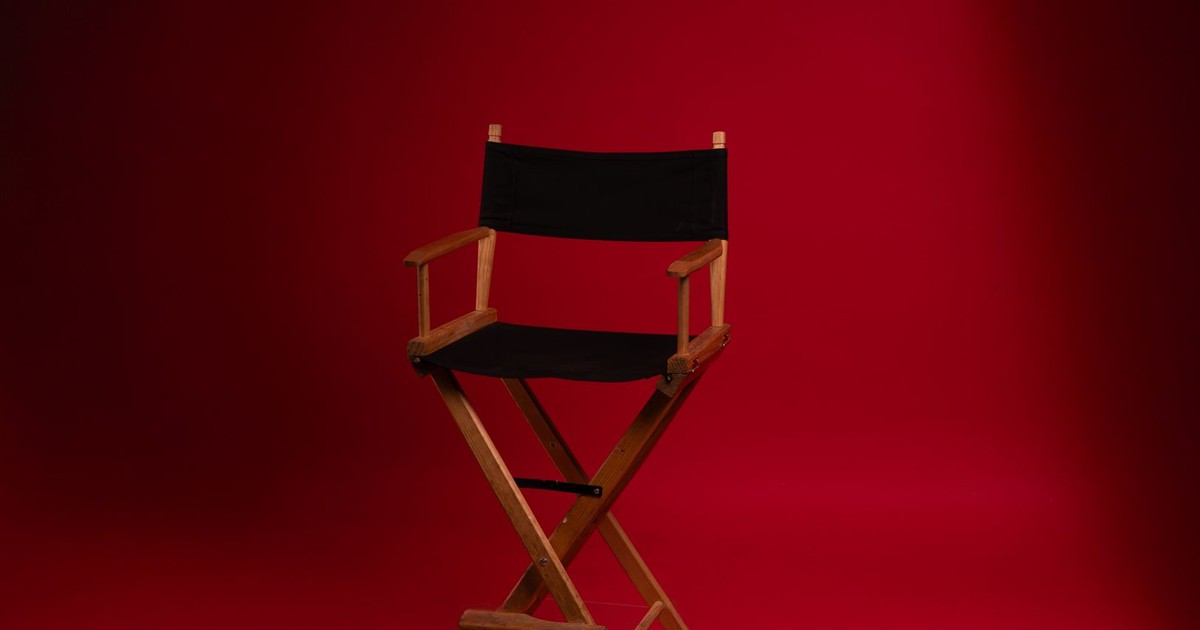 A wooden director's chair against a vibrant red backdrop, symbolizing film industry authority.