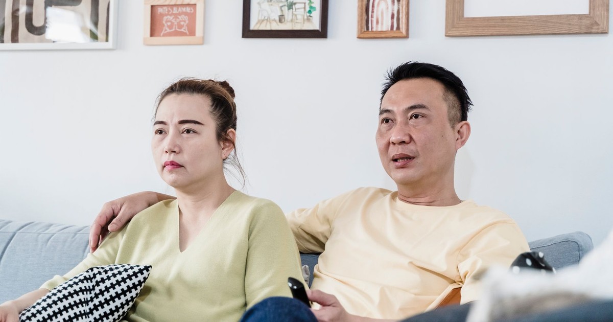 A couple sitting on a comfortable sofa at home in a cozy living room, enjoying a relaxed moment together.