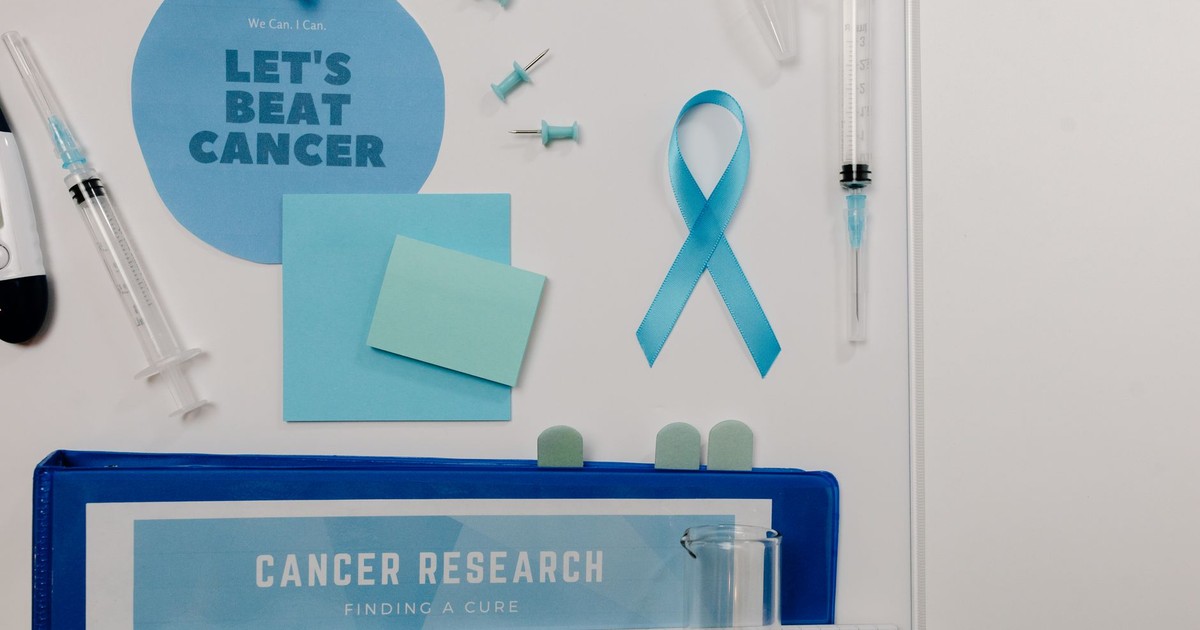 Flat lay showing cancer awareness items with blue ribbon and research tools.