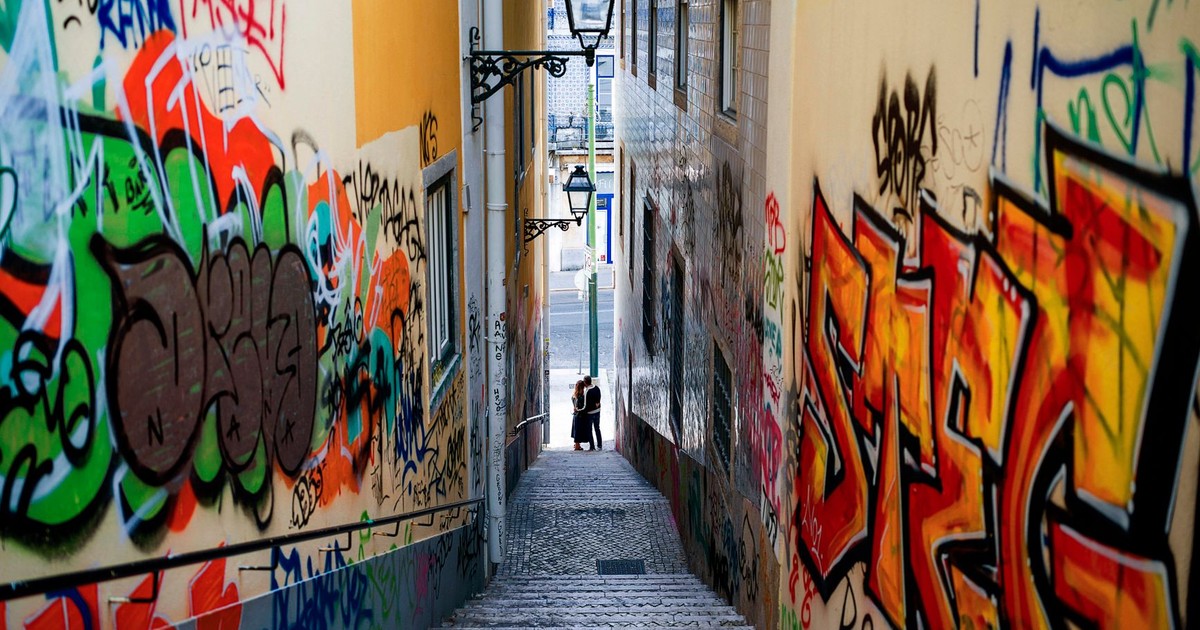 Vibrant graffiti decorates a narrow alley in Lisbon, Portugal, offering a glimpse of urban art.