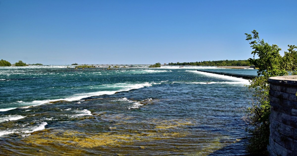 A serene view of the Niagara River in Ontario, Canada, under a clear blue sky.