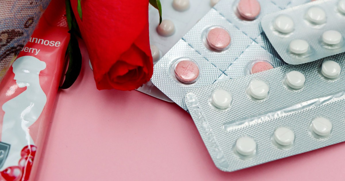 Pills and red rose on pink background, symbolizing healthcare and romance.