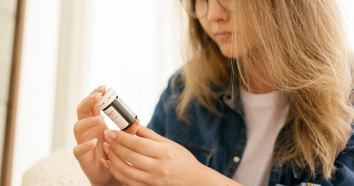 A woman carefully examines a medication bottle indoors, emphasizing health care attention.