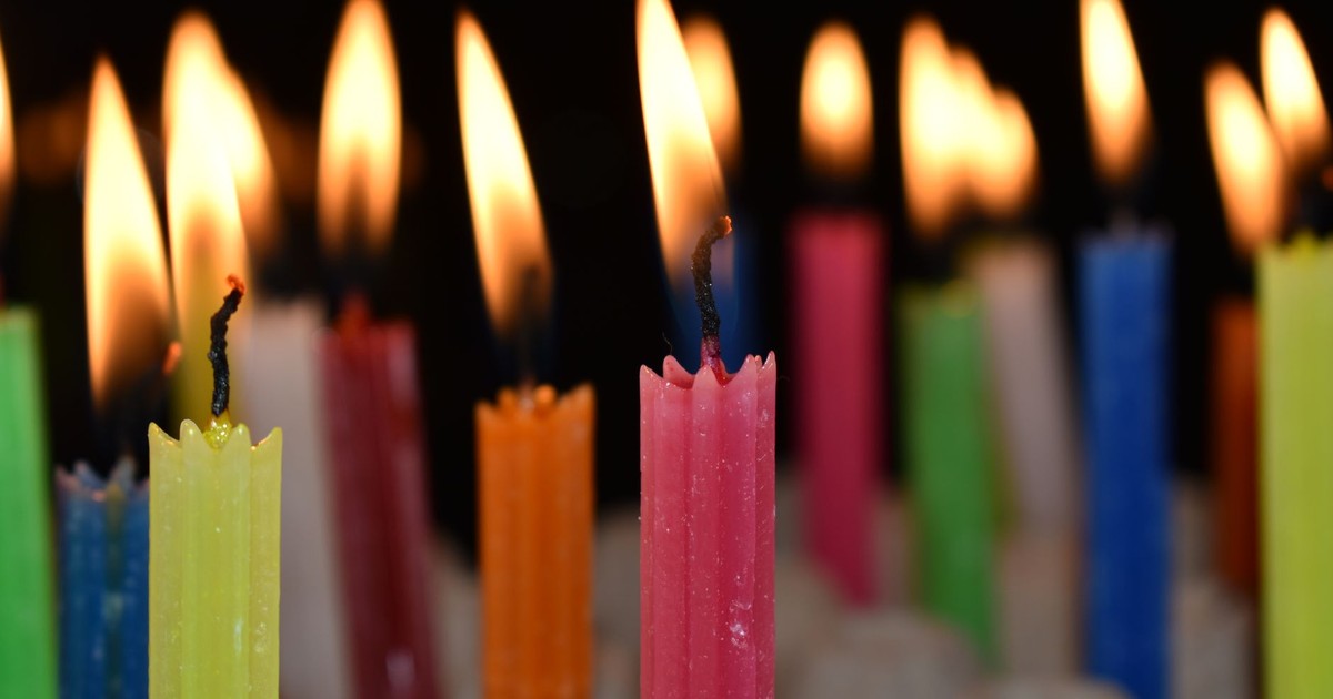 Close-up of colorful wax candles with vibrant flames in low light.