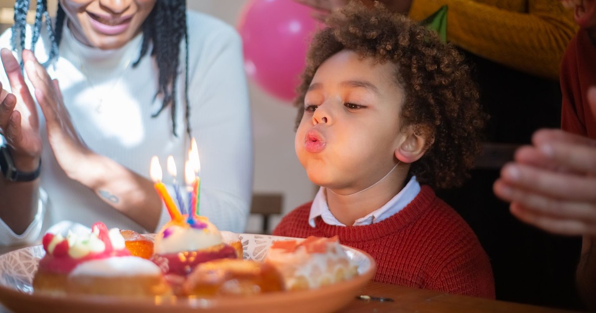 A joyful birthday celebration with a child blowing out candles surrounded by family, capturing a happy moment.