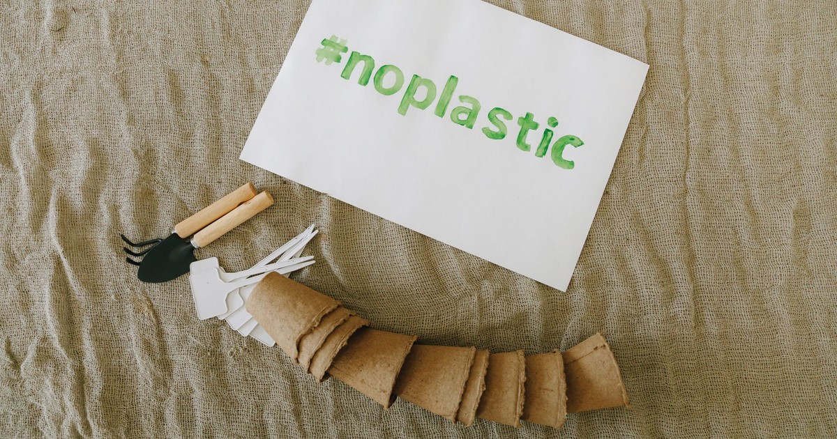 Top view of sustainable gardening tools on fabric with '#noplastic' sign.