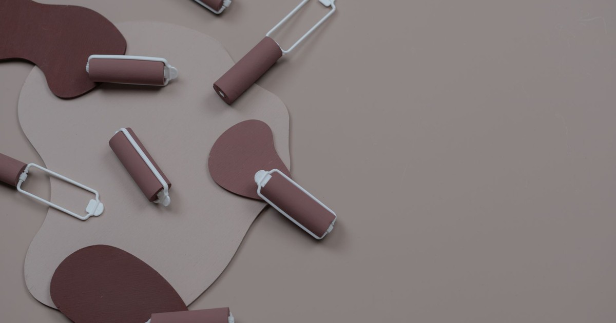 Brown paint rollers arranged on an abstract background, creating a minimalist and conceptual design.