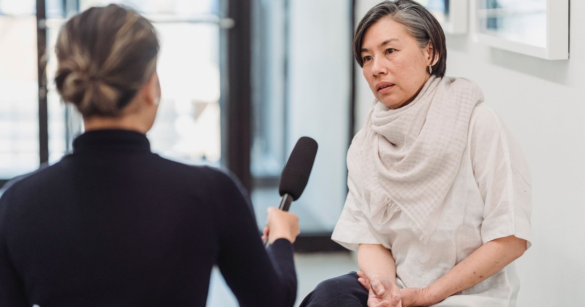 Professional interview setting with a female journalist and woman discussing indoors.