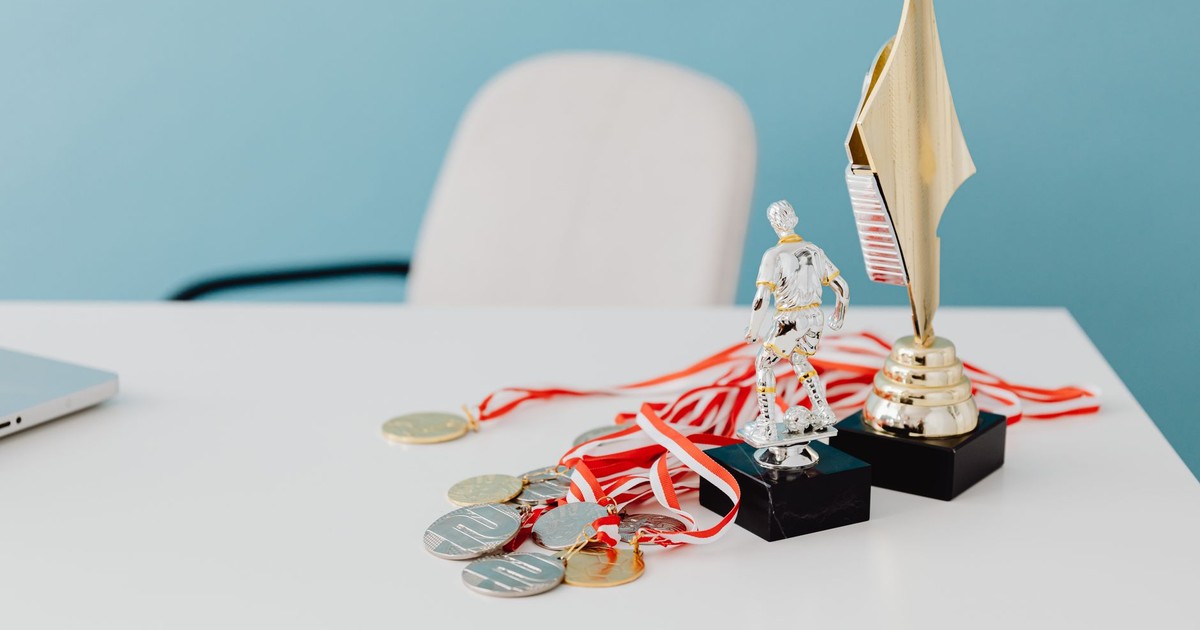 A collection of trophies and medals displayed on a white desk, symbolizing success and victory.