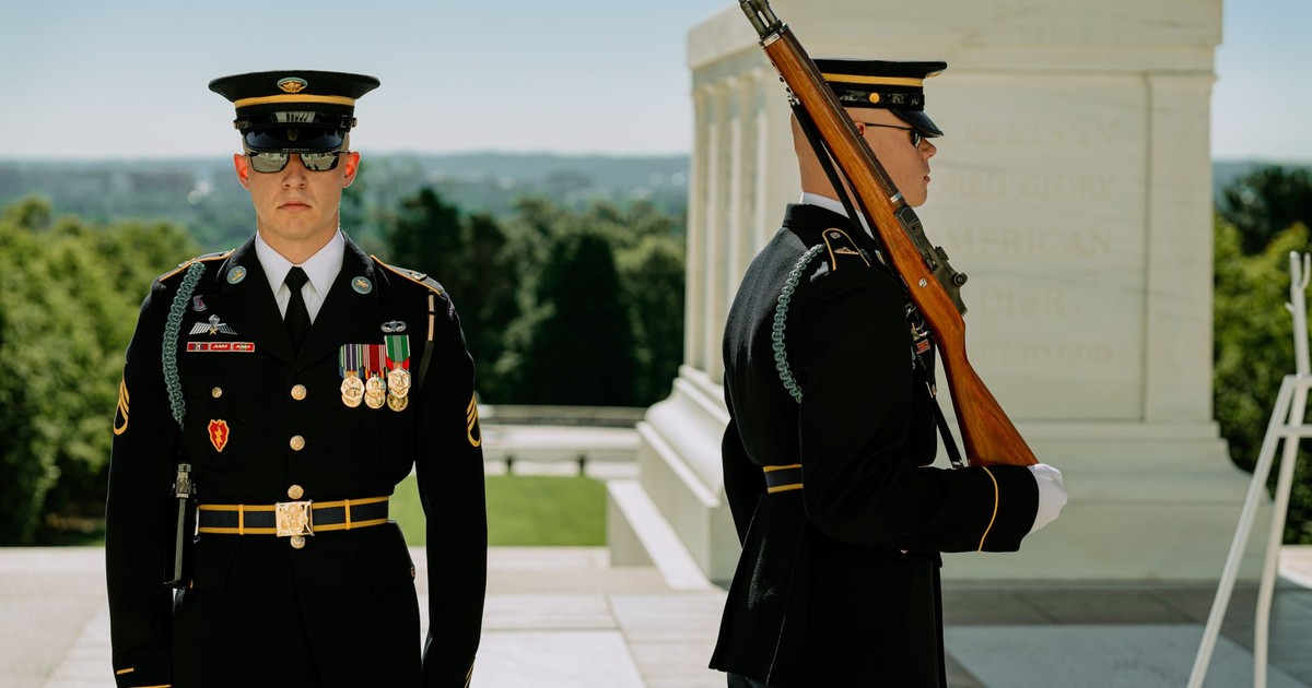 Uniformed military guards perform ceremonial duties outdoors at a national monument.