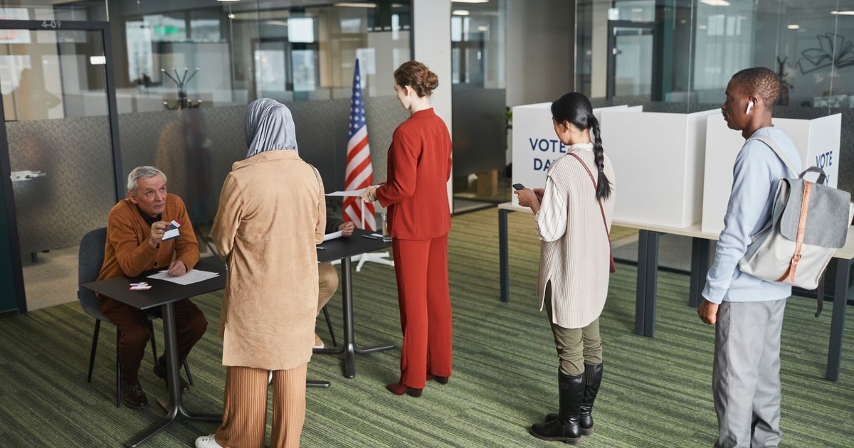 Diverse group of voters lining up at an indoor polling station on election day.