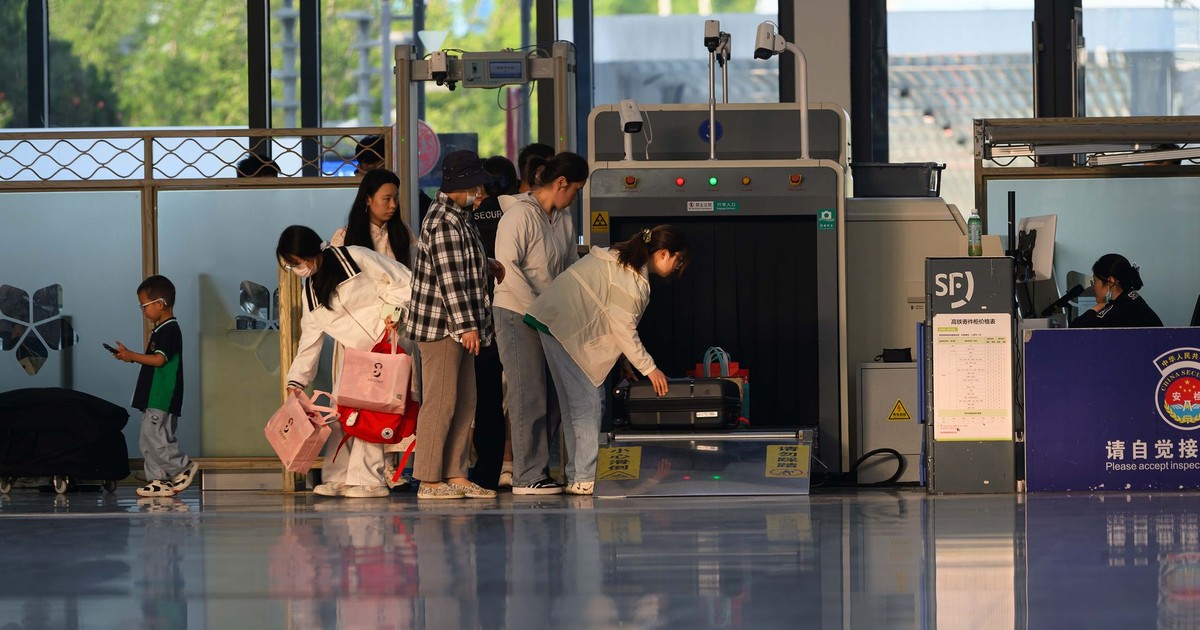 Travelers undergo security screening at an airport terminal.