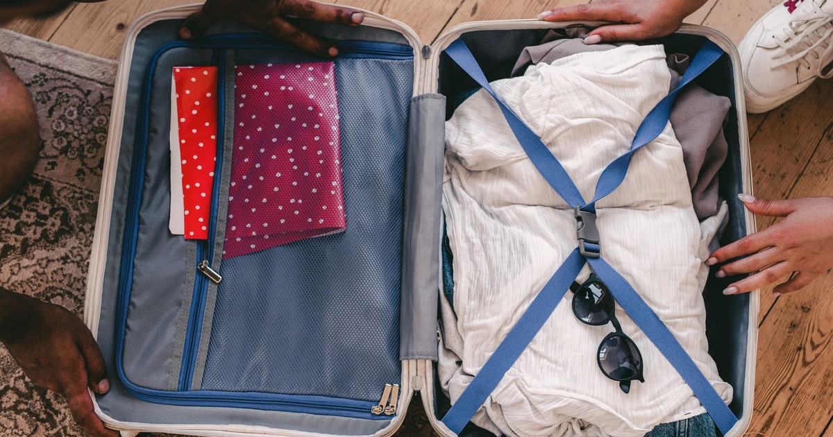 A neatly packed open suitcase with clothing and travel essentials, ready for a trip.