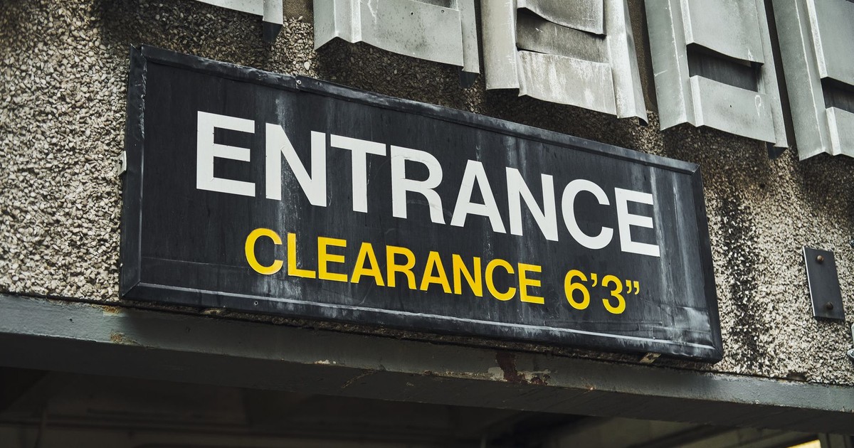 Close-up of an entrance clearance sign on a building, indicating height limit.