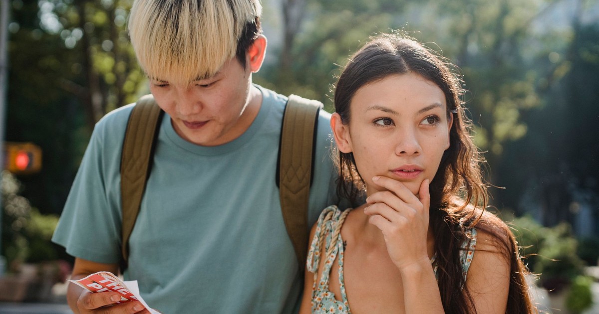 Confused multiracial couple searching way in map while discovering city together during summer holidays
