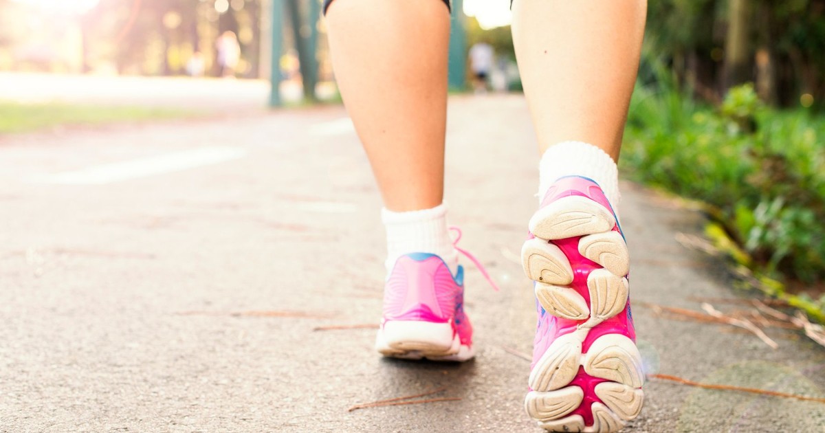 Close-up of a woman walking on a path in pink sneakers, embracing fitness and an active lifestyle.
