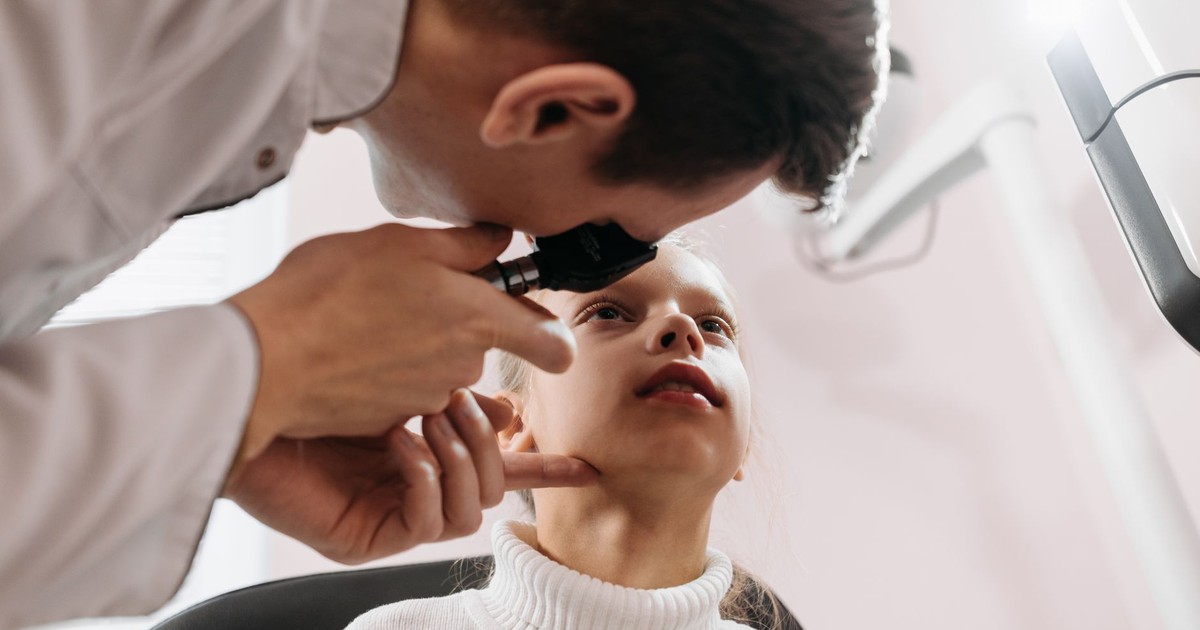 Doctor performs an eye examination on a young girl in a clinic setting, showcasing pediatric healthcare.