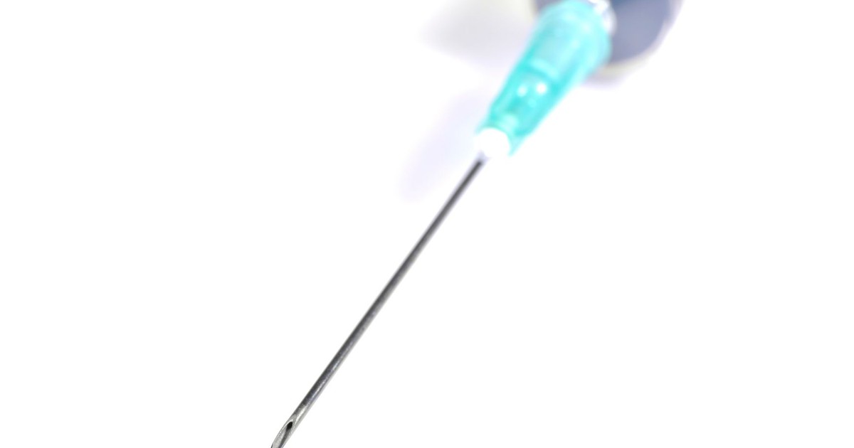 Macro shot of a medical syringe needle on a white background, ideal for healthcare themes.