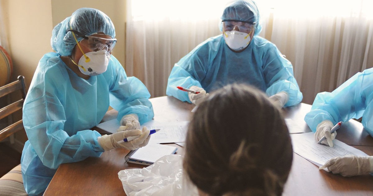 Healthcare professionals in PPE discuss operations during a meeting indoors.