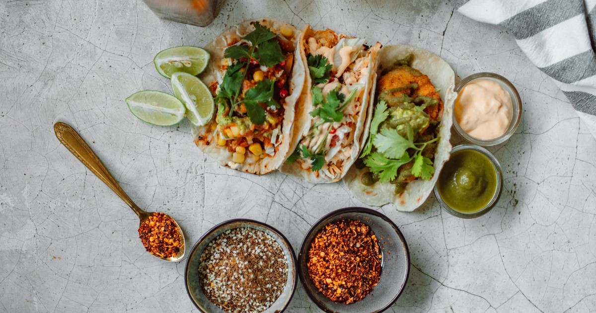 Top view of colorful Mexican tacos with limes, spices, and sauces, perfect for a culinary splash.