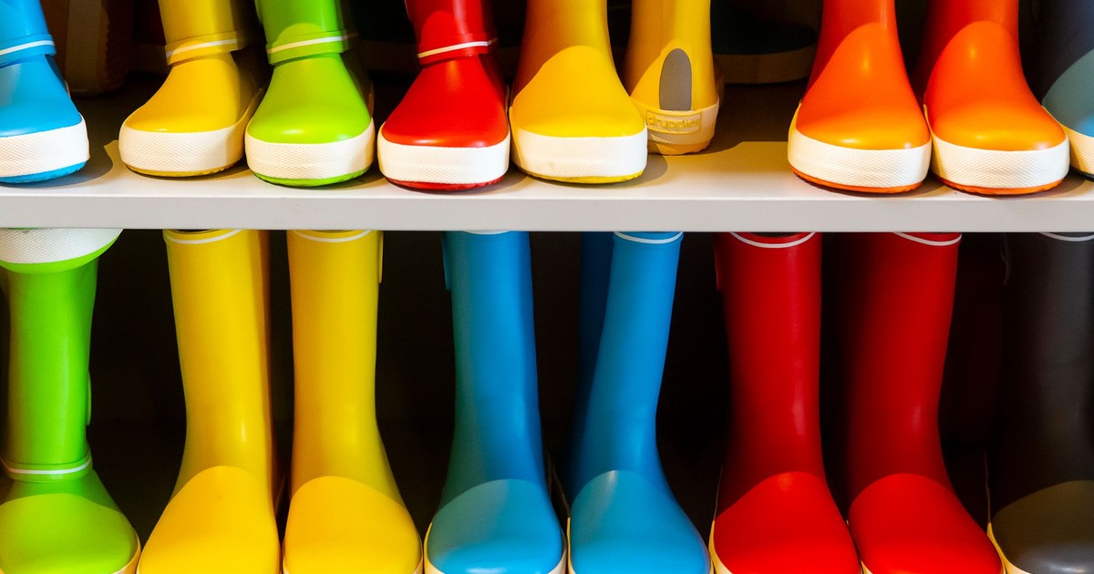 A vibrant collection of rubber rain boots in various colors neatly arranged on a shelf.