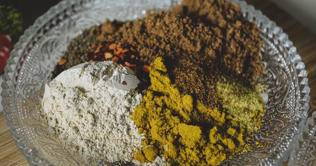 A close-up shot of various spices and powders in a decorative glass bowl.
